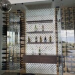 The back section of the wine cellar is adorned with mirrored tiles, creating a dynamic and dramatic aesthetic.